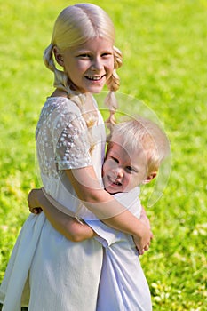 Little excited boy hugging his sister strongly