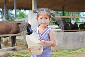 Little farmer girl holding milk bottle in farm. Feeding the murrah buffalo in farm