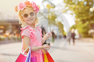 Little fashion girl wearing sunglasses and holding shopping bags