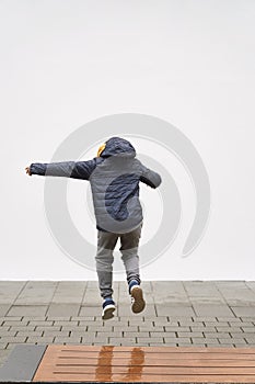 Little fashionable boy posing in front of white concrete wall. Concept of style and fashion for children