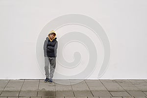 Little fashionable boy posing in front of white concrete wall. Concept of style and fashion for children