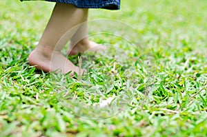 Little feet baby walking on green grass