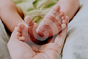 Little feet of newborn baby in mother`s hand. Baby birth, maternity concept.
