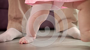 Little feet walking on floor. Child steps with father support