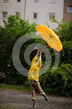 Malý člověk v jasný pláštěnka mouchy přes země deštník v ruce 