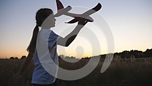 Little female child walking with plane in hand through country road at dusk time. Carefree small girl going with toy on