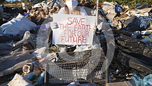 Little female eco volunteer holds in hands placard of environmental movement for saving earth. Small girl in protective