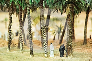 Little figurines of Arabs in the desert oasis under the palm trees photo