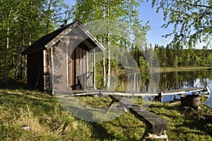 Little fishing cottage at the lake shore surrounded by birch trees