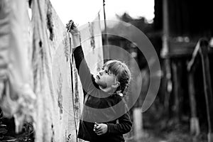 Little five-year girl with clothespin outdoor. Black and white photo.
