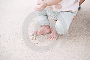 Little foot of baby girl on sandy beach. Walking on sand for the first time.