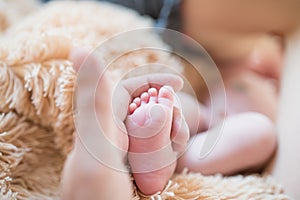 Little foot in hand. Father holding the legs of a newborn in his hands. Mom cares for the baby after taking a bath. Parents to