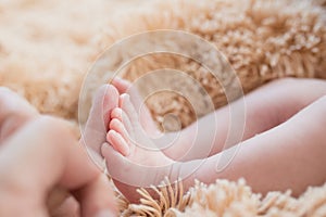 Little foot in hand. Father holding the legs of a newborn in his hands. Mom cares for the baby after taking a bath. Parents to