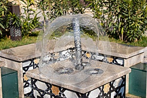 Little fountain. Transparent falling water vertical flows, close up