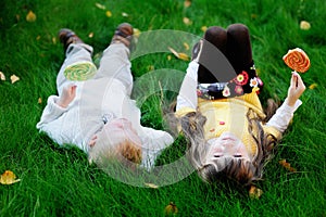 Little friends eating lollipops together on a lawn