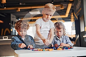Little friends have fun with construction toys in playroom. Kindergarten educational games