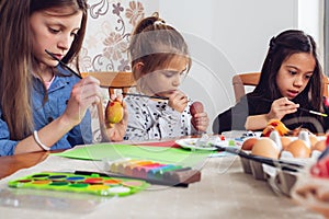 Little friends painting Easter eggs before holiday