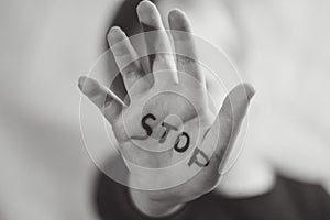 Little frightened girl shows the word `Stop` written on the arm. Children are subjected to violence and publishing in the home and