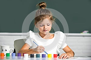 Little funny artist painting, drawing art. Cute little girl child painting with paints color and brush. Drawing lesson