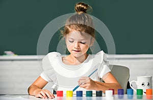 Little funny artist painting, drawing art. Cute little girl child painting with paints color and brush. Drawing lesson