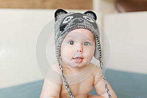 Little funny baby boy with big blue eyes smiling with cute cap with ears on his head