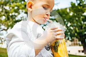 Little funny boy drinking a fresh  lemonade