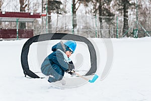 Little funny boy with her mother skating in the park. Play ice hockey with stick and goal. Outdoor. Winter sport