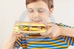 Little funny boy is licked at cheeseburger on white background