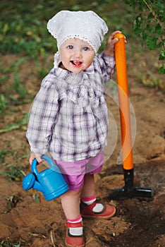 Little funny boy with shovel in garden