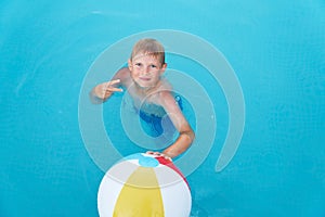 Little funny boy in the swimming pool with ball