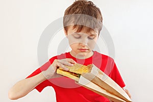 Little funny boy take out a cheeseburger from a package on white background