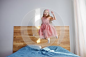 Little funny little child girl in motion jumping on bed alone flying in air feeling joy