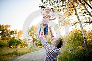Little funny girl being thrown up in the air by her father