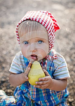 Little funny girl eates a pear