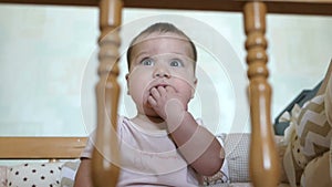 Little funny girl standing in baby bed and laughing. Happy childhood concept