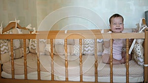 Little funny girl standing in baby bed and laughing. Happy childhood concept
