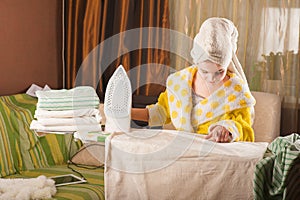 Little funny housewife with iron. Iron in the hand of the girl on the Ironing Board irons and steams clothes. Little girl playing