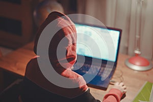 Little gamer kid in hood playing mass multiplayer game online on laptop