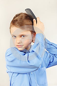 Little gentleman in a bright shirt brushing her hair hairbrush