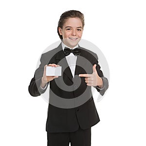 Little gentleman. Cheerful little boy in formalwear holding business card and smiling while isolated on white photo