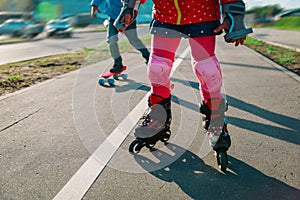 Little gilr on roller skates and boy on skateboard outside