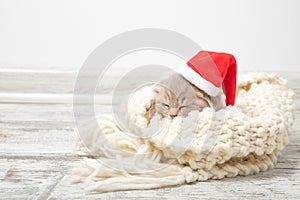 Little ginger kitten sleeps in a Christmas hat