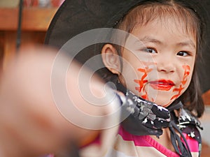 Little girl, 3 years old, is happy with her Halloween makeup and pretend playing as a powerful witch