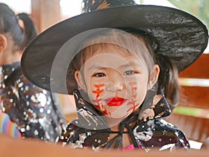 Little girl, 3 years old, is happy with her Halloween makeup, stitches, wound, on her face done by herself before attending her