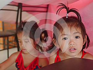 Little girl, 3 years old right, together with her sister, enjoy staying in house built by themselves out of cardboard boxes,