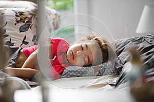 A little girl of 3 years old is sleeping sweetly on her side.