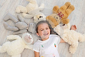 A little girl 5-6 years old lies among Teddy bears