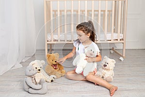 Little girl 5-6 years old playing in the children`s room with Teddy bears