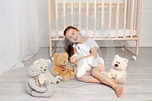 Little girl 5-6 years old playing in the children`s room with Teddy bears