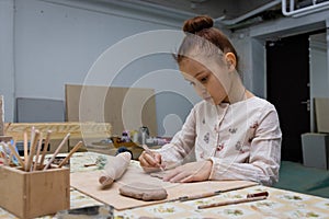 A little girl of 6 years sculpts a heart from clay. preparing a gift for mother`s day
